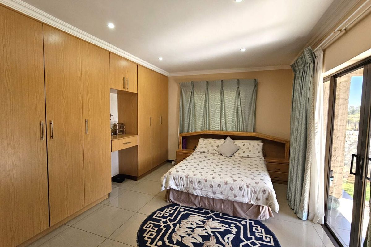 A well-maintained bedroom featuring extensive built-in wooden cabinetry, tiled flooring, and sliding glass doors providing direct access to the outdoor area.