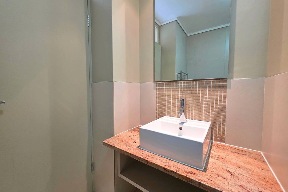 A modern bathroom vanity featuring a square vessel sink, granite countertop, and mosaic tile backsplash with a wall-mounted mirror.