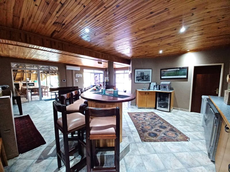 Spacious entertainment area featuring a built-in bar, timber-clad ceiling, tiled flooring, and integrated cabinetry with a sink, perfect for hosting guests.