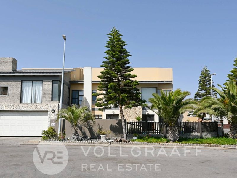 Front elevation of a modern double-story house featuring stone cladding, a double garage, and established landscaping.