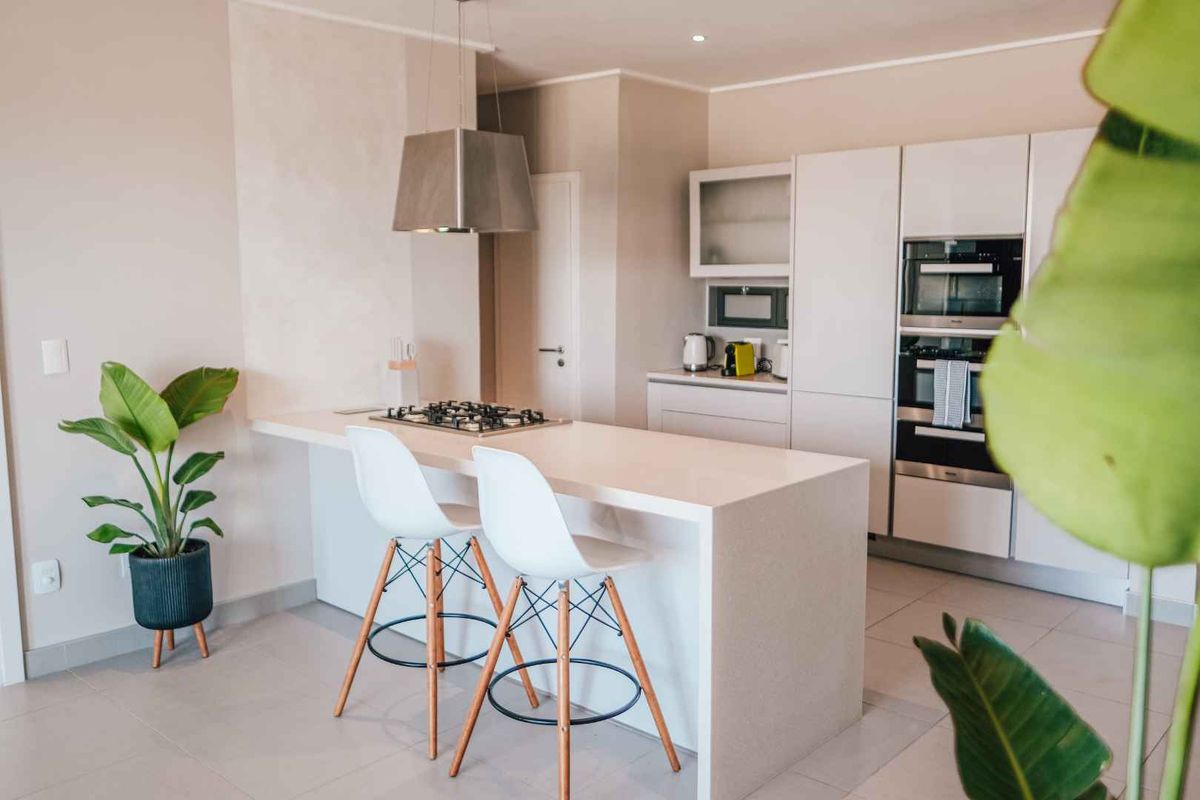 Modern kitchen featuring a central island with integrated gas hob, stainless steel extractor, and built-in oven and microwave units.
