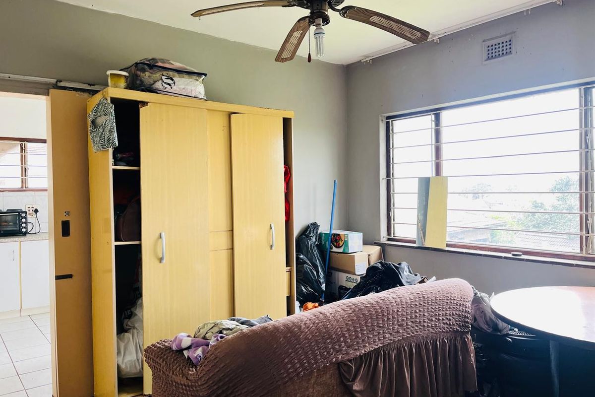 A bedroom featuring a ceiling fan and security bars on the window, requiring cosmetic updates to improve the overall condition and appeal.