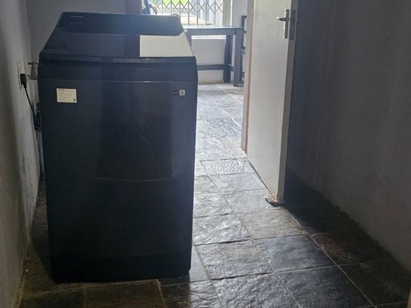 A functional laundry area featuring durable tiled flooring and direct access to an exterior space through a secure door.