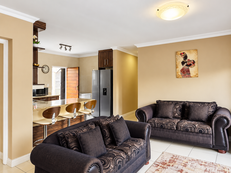 An open-plan living and kitchen area featuring tiled flooring, granite countertops, and a breakfast bar, creating a functional and connected living space.