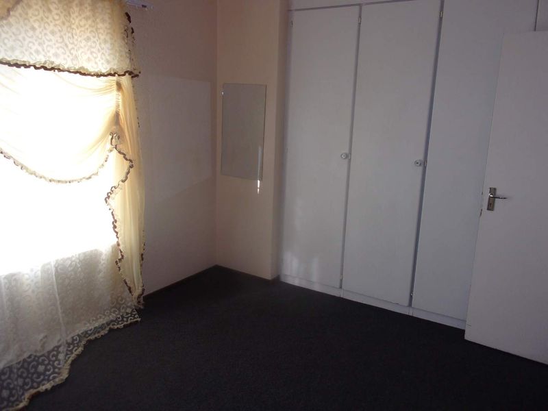 A vacant bedroom featuring built-in cupboards and carpeted flooring, offering a neutral space ready for personalization.