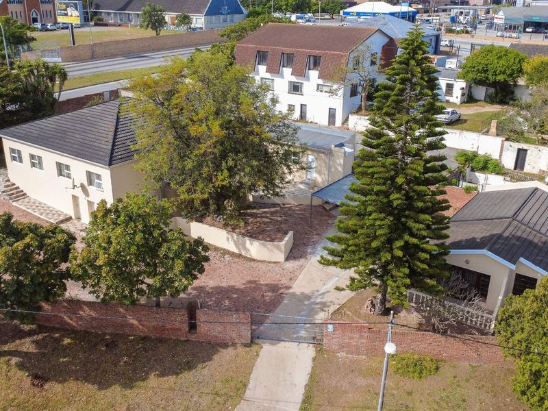 Aerial view of the property showing the main building, driveway, mature trees, and brick boundary wall with gated access.