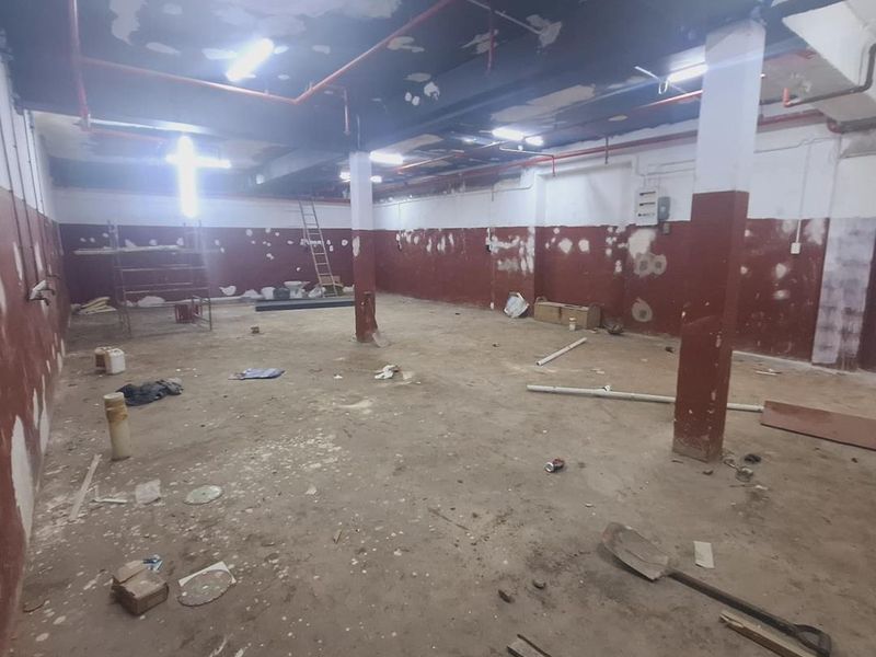 An expansive, unfinished industrial utility space featuring exposed ceiling infrastructure, structural columns, and raw wall finishes, suitable for renovation or storage.