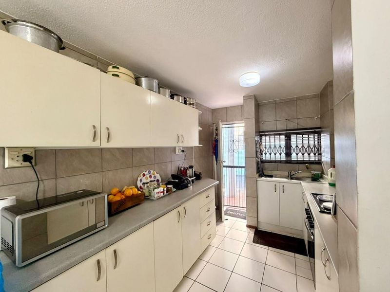 Functional kitchen featuring ample built-in cabinetry, tiled backsplash, and direct access to an outdoor area through a secure door.