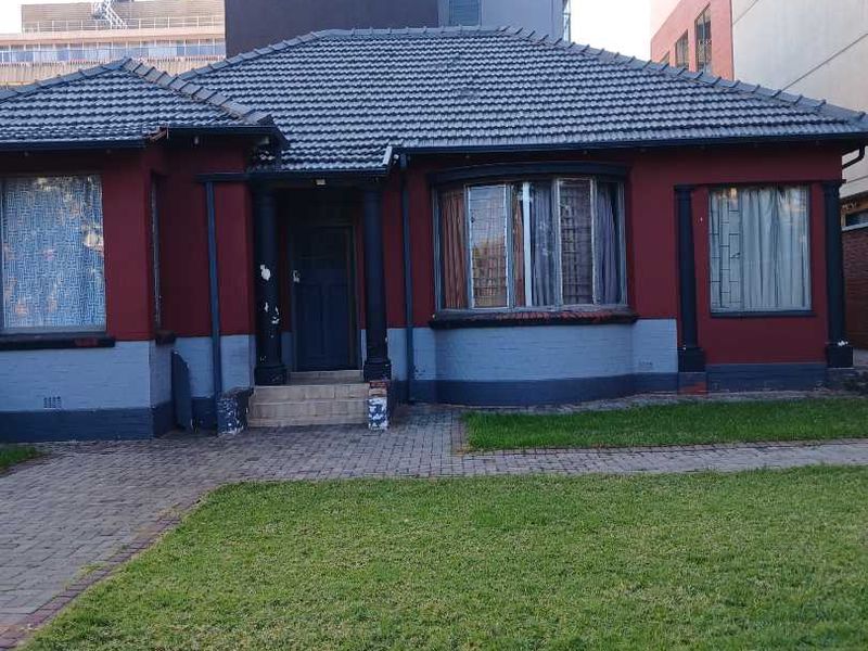 Front elevation of a single-story residential property featuring a tiled roof, bay window, and paved driveway area.