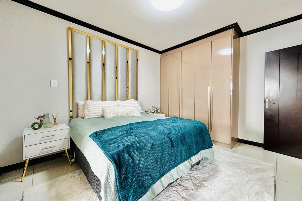 A well-maintained bedroom featuring built-in high-gloss cabinetry, a decorative metallic headboard feature, and tiled flooring.