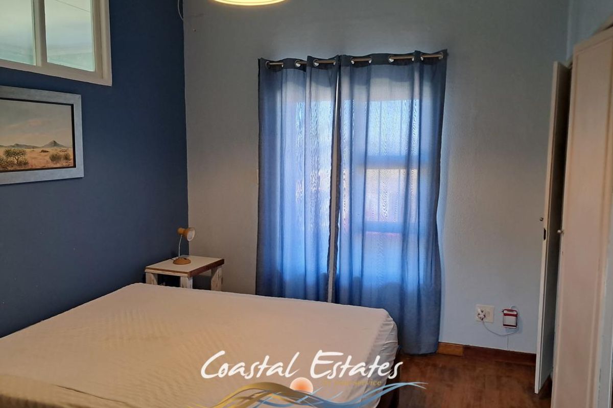 A bedroom featuring blue accent walls, wood-look flooring, and a window with curtains.