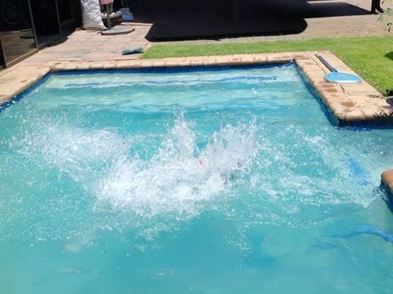 Outdoor pool area featuring a swimming pool, paved patio, and a covered pergola structure in the rear garden.
