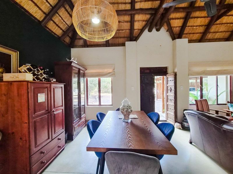 Spacious dining area featuring a high vaulted thatched ceiling with exposed timber beams and tiled flooring, creating a rustic and inviting atmosphere.