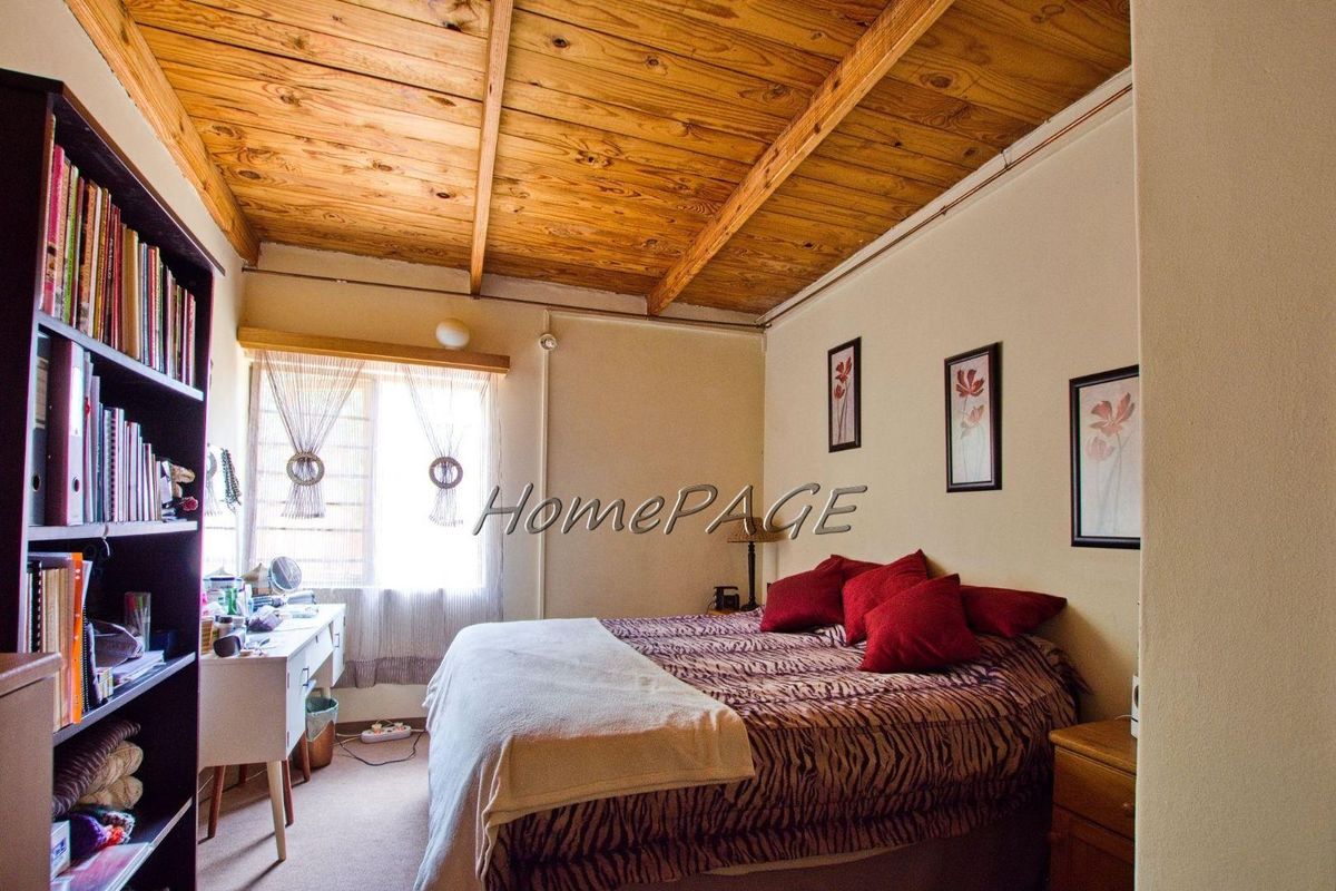 A cozy bedroom featuring a rustic exposed timber beam ceiling and neutral wall finishes.