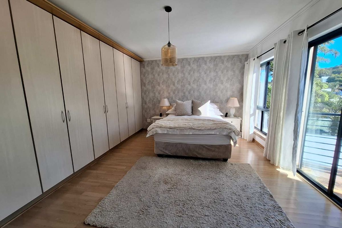 Spacious bedroom featuring extensive built-in wardrobes, light laminate flooring, and large sliding glass doors providing natural light and access to an outdoor area.