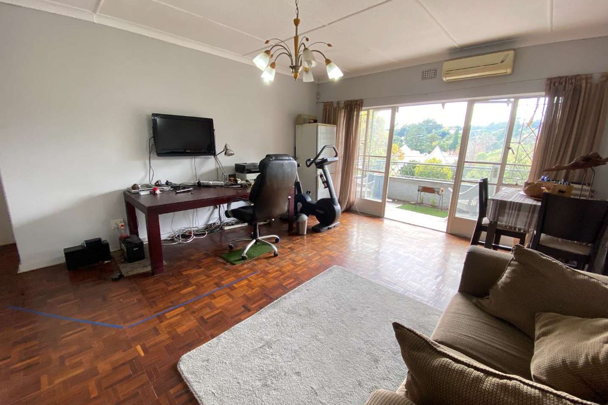 Spacious living area featuring parquet flooring, a wall-mounted air conditioning unit, and large sliding glass doors opening onto a balcony with scenic views.