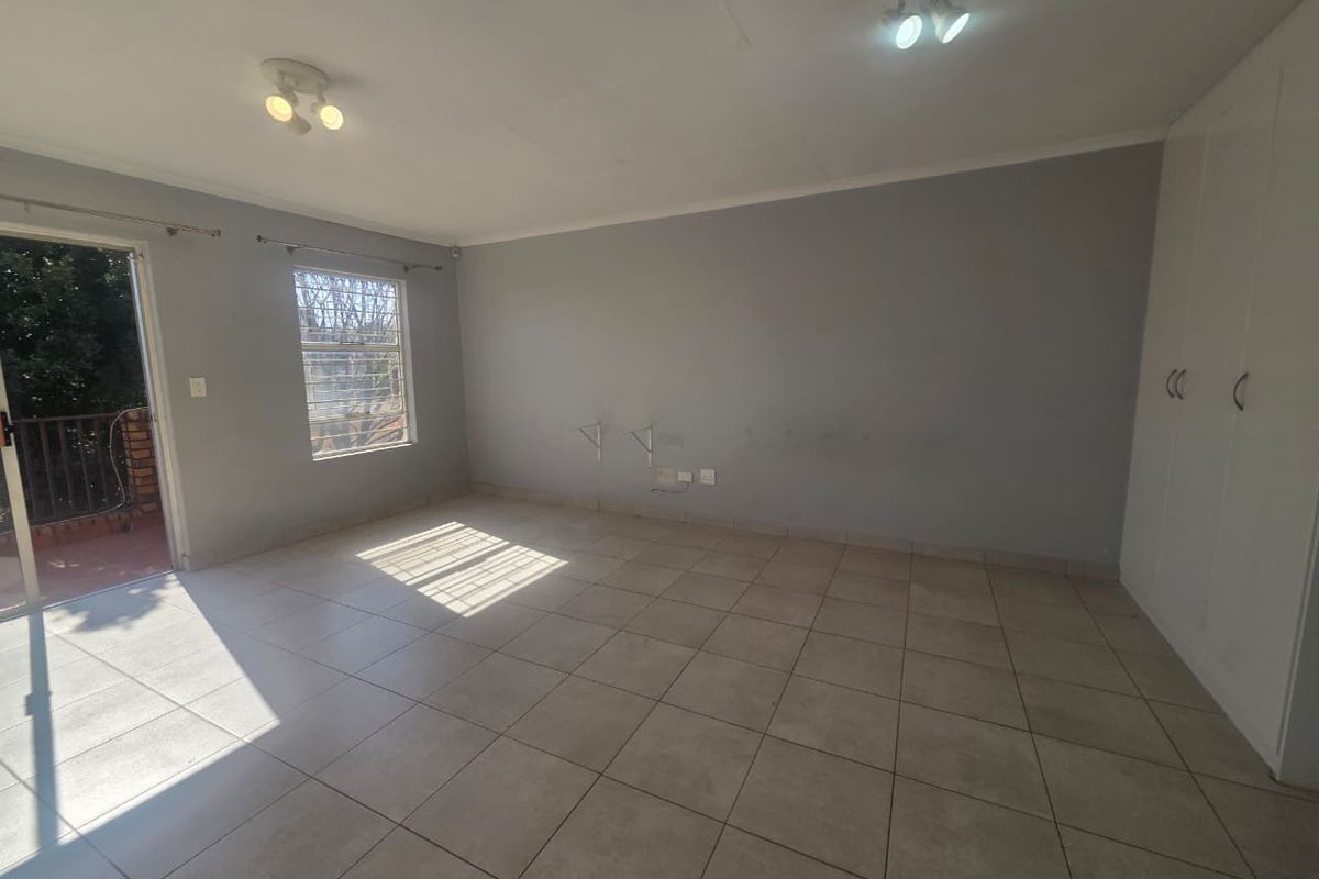 An empty bedroom featuring tiled flooring, built-in cupboards, and a sliding door providing access to an outdoor balcony area.