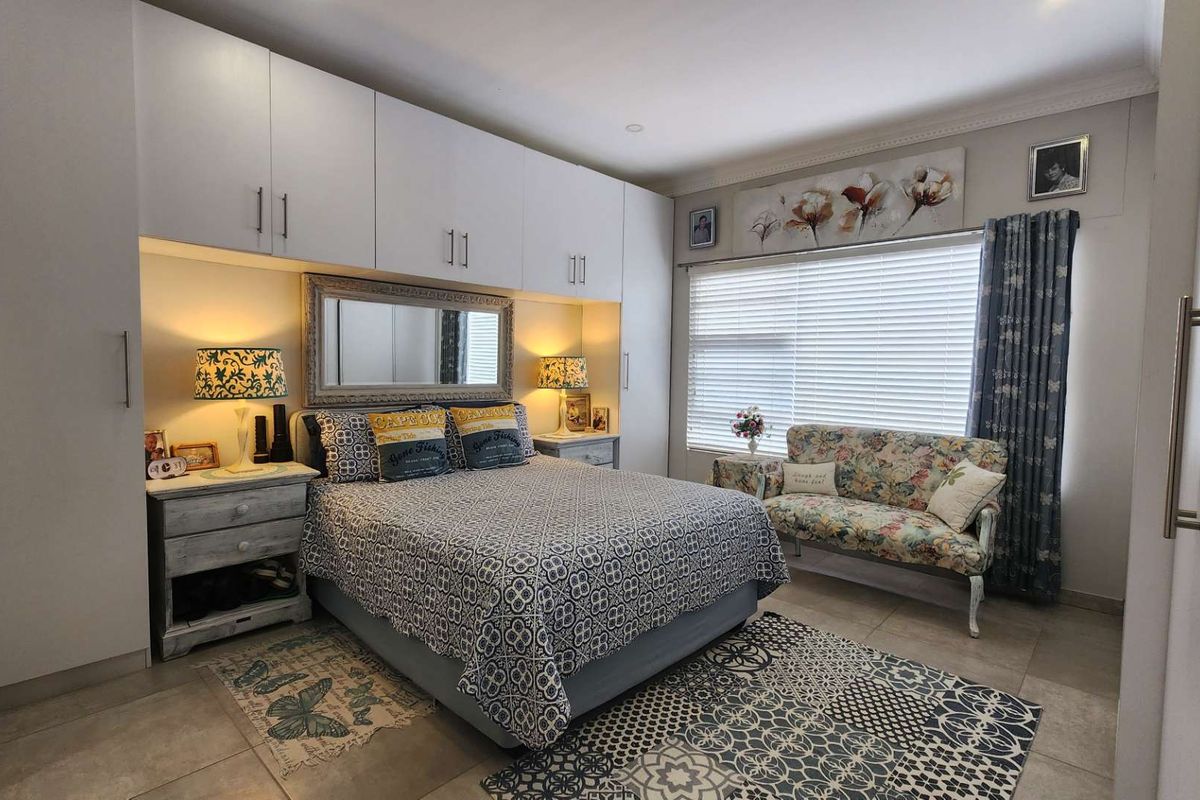 A well-maintained bedroom featuring extensive built-in cabinetry, tiled flooring, and large windows with venetian blinds for natural light control.