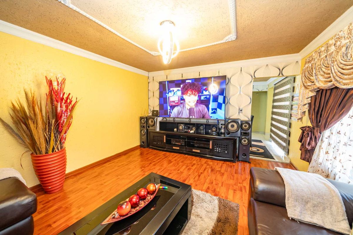 A living room featuring wood-look flooring, decorative ceiling molding, and a central light fixture, providing a functional space for entertainment.