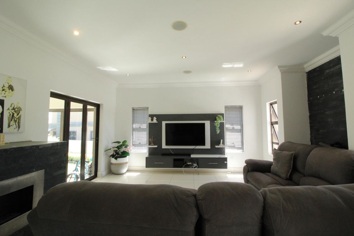 Spacious living room featuring a built-in media unit, recessed ceiling lighting, tiled flooring, and direct access to the patio through glass sliding doors.