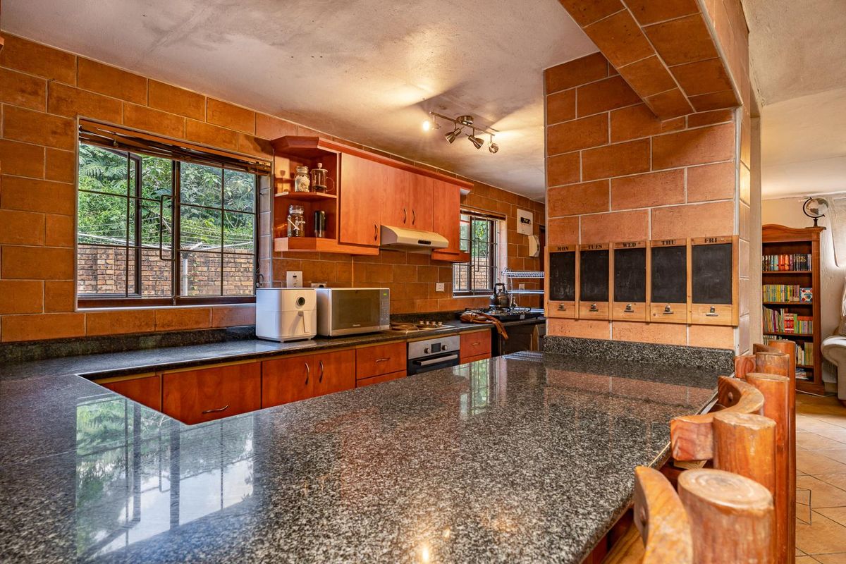 A rustic kitchen featuring granite countertops, wooden cabinetry, and distinctive brick-tiled walls, offering a warm and functional cooking space.
