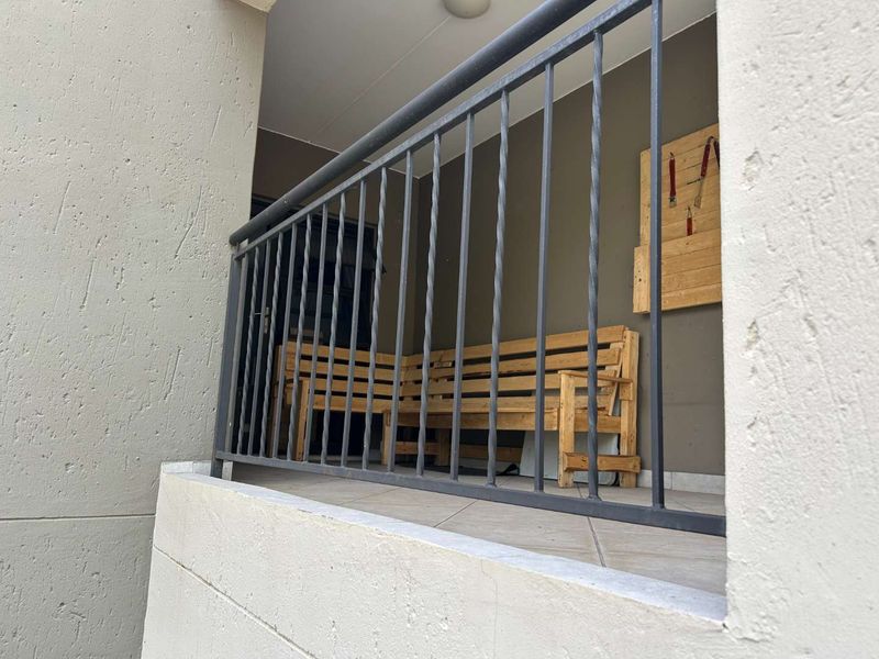 A covered balcony area featuring tiled flooring and a metal balustrade, providing a functional outdoor space for the townhouse.