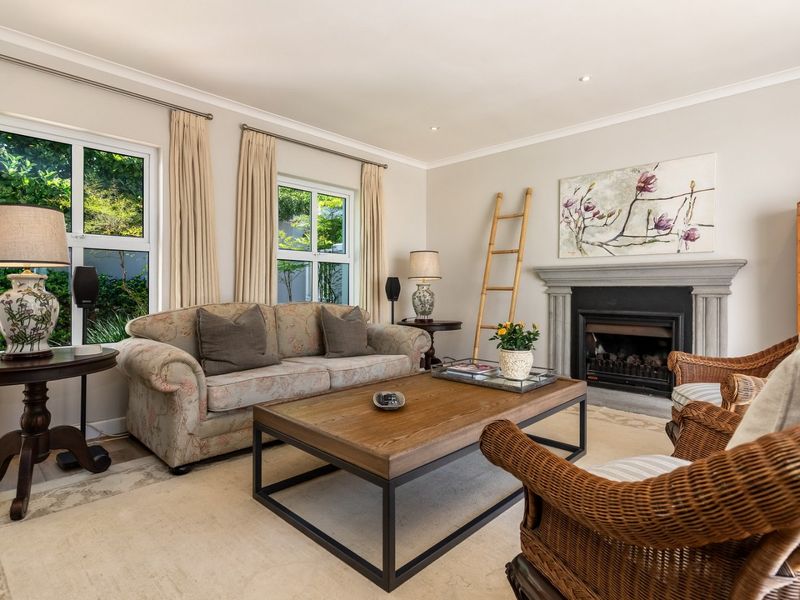 A well-maintained living room featuring a classic stone fireplace, recessed lighting, and large windows that provide ample natural light.
