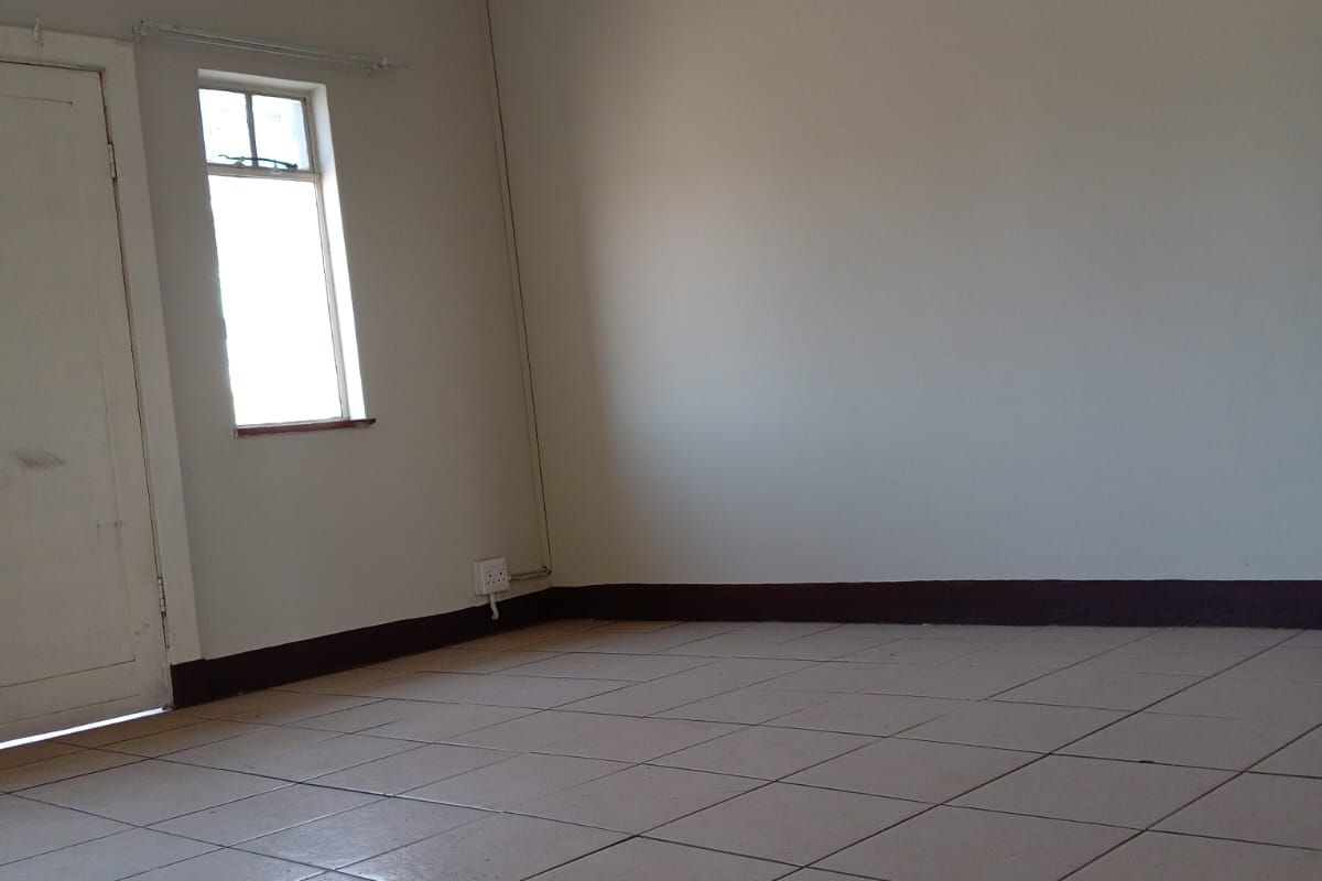 An empty living room featuring tiled flooring, decorative pressed metal ceilings, and traditional cornice detailing, awaiting renovation or staging.