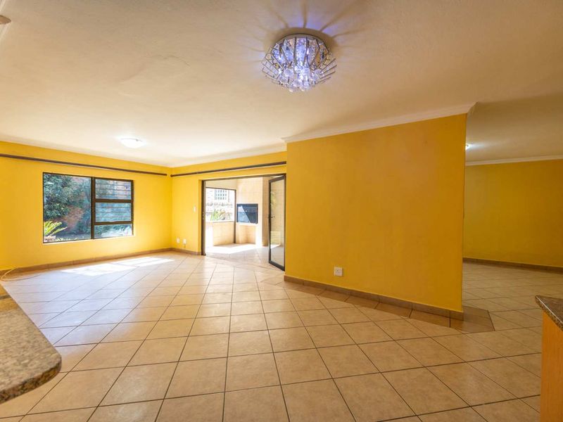 Spacious open-plan living area featuring tiled flooring, neutral walls, and direct access to an outdoor patio through sliding glass doors.