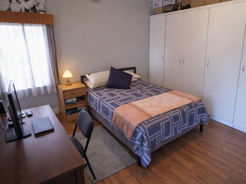 A functional bedroom featuring laminate flooring and a large built-in wardrobe providing ample storage space.