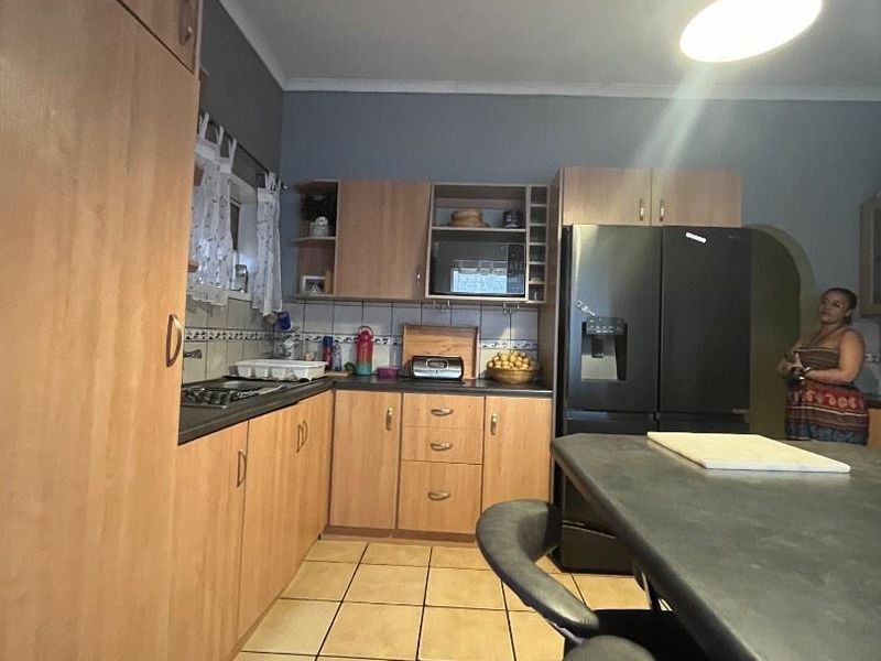 Functional kitchen featuring laminate cabinetry, tiled flooring, a central island, and built-in appliances, offering a practical layout for daily cooking and dining.
