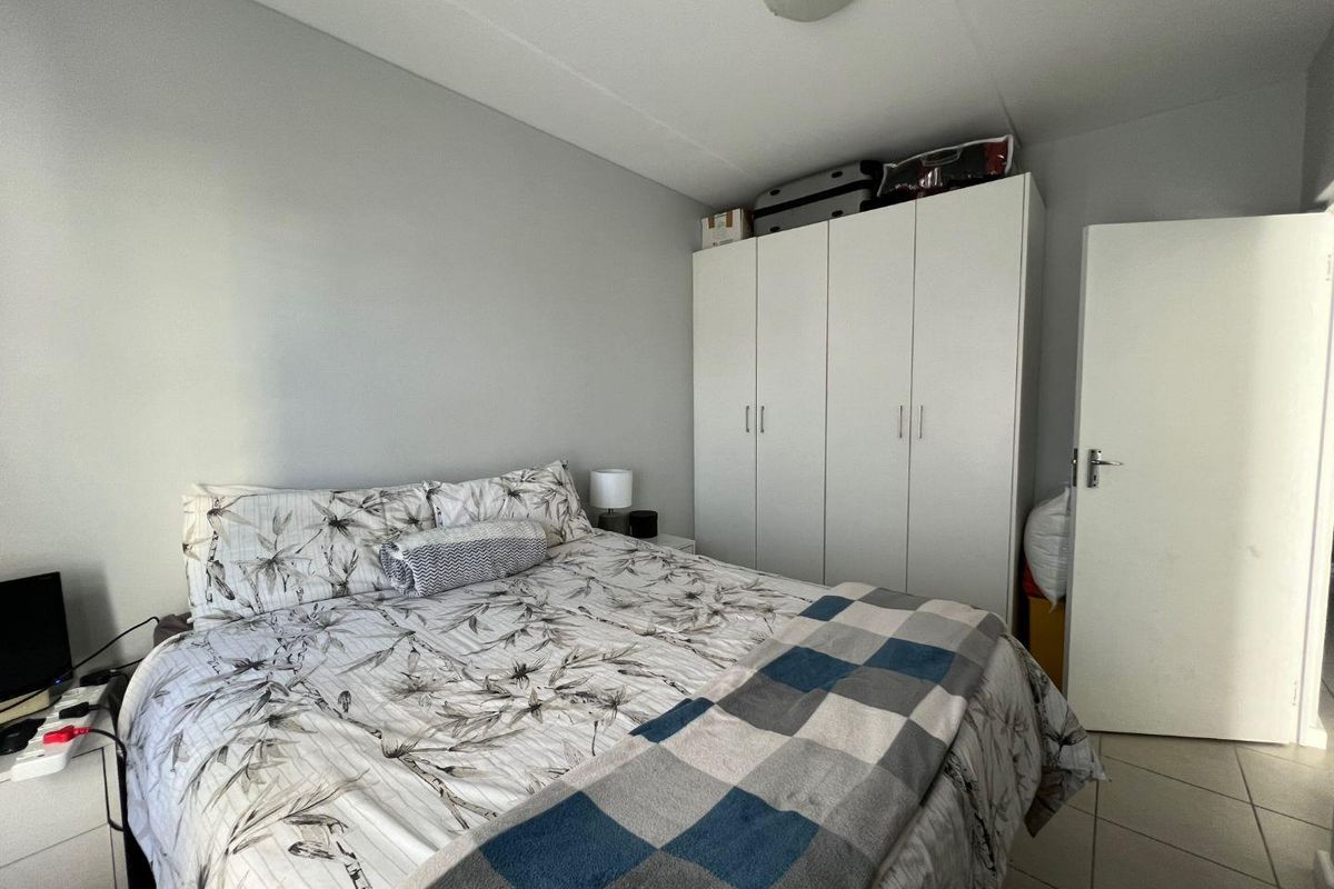 A functional bedroom featuring built-in white cabinetry and tiled flooring, providing practical storage and a neutral living space.