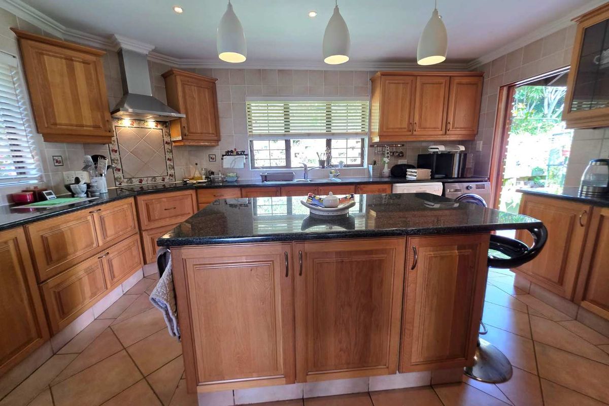 Spacious kitchen featuring wooden cabinetry, granite countertops, a central island, and tiled flooring with direct access to the outdoor area.