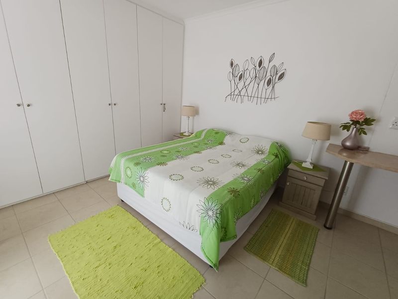 A bedroom featuring neutral tiled flooring and extensive white built-in cupboards providing ample storage space.