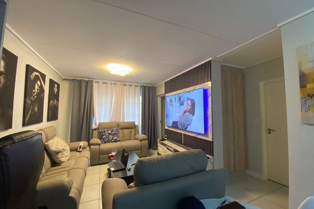 A comfortable living room featuring a decorative slat wall panel, tiled flooring, and neutral wall finishes.