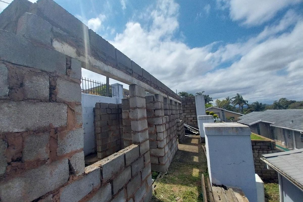 An exterior view of a property under construction, featuring exposed concrete block walls and structural masonry work in progress.