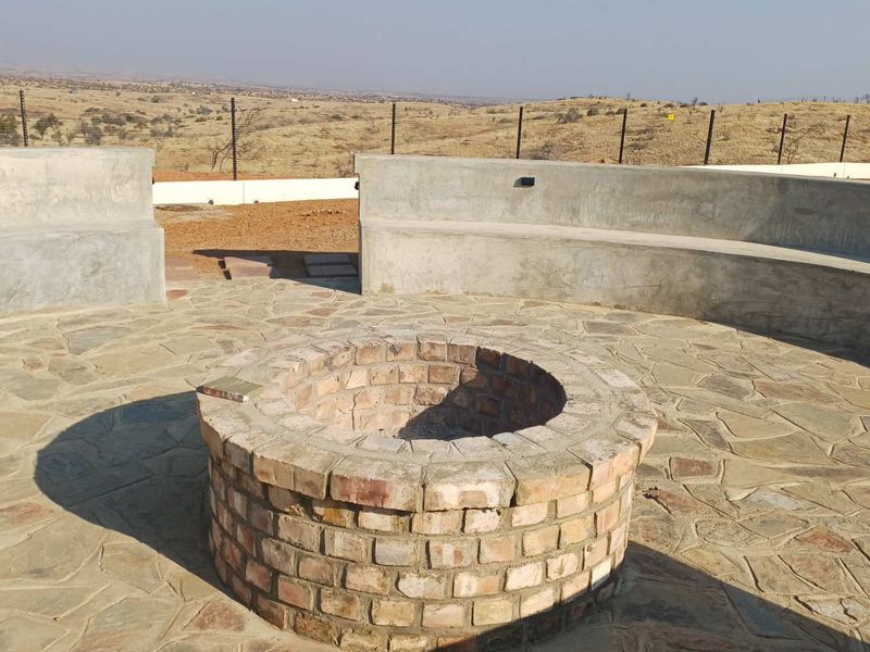 Outdoor entertainment area featuring a circular brick fire pit and built-in concrete bench seating with expansive landscape views.