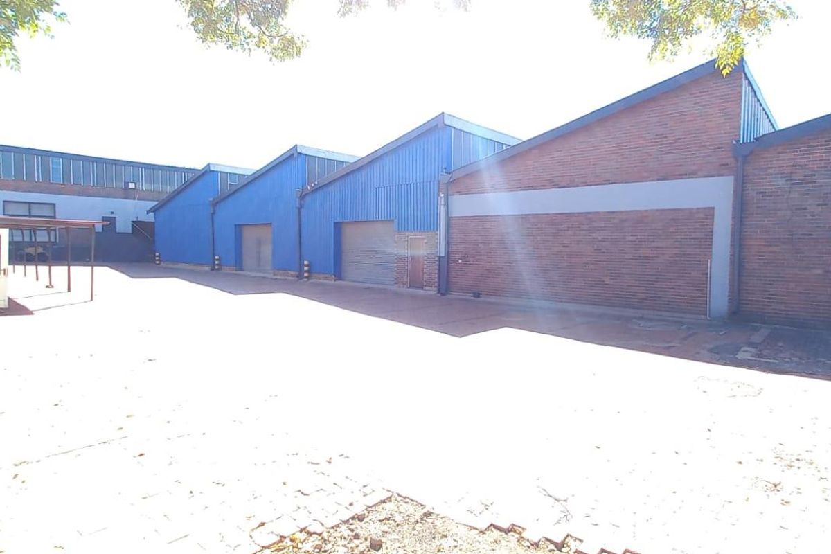 Exterior view of an industrial property featuring multiple warehouse units with metal cladding, brick facades, and a paved yard area.
