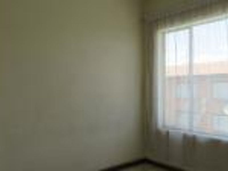 A bright, empty bedroom featuring a large window with natural light, suitable for a variety of bedroom configurations.