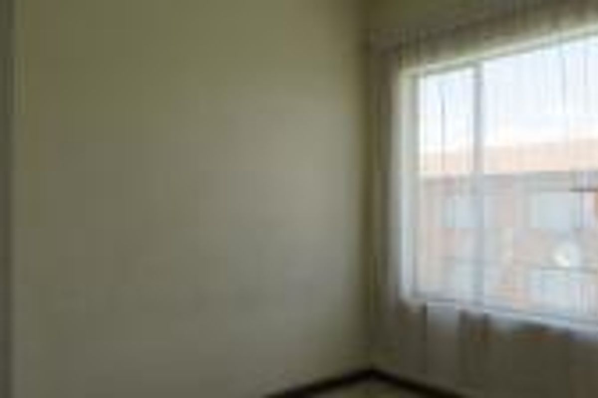 A bright, empty bedroom featuring a large window with natural light, suitable for a variety of bedroom configurations.