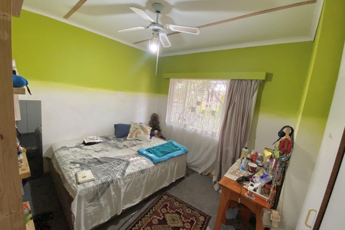 A bedroom featuring a ceiling fan, large window with security bars, and two-tone wall paint.