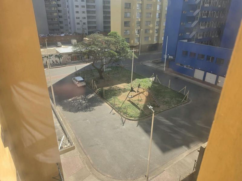 An elevated view overlooking a local street and a small public park area with surrounding apartment buildings.