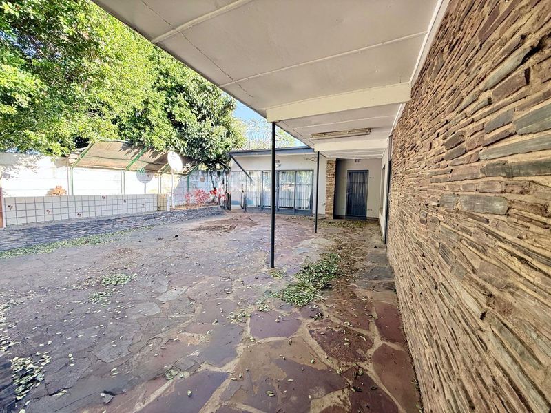 A spacious covered patio area featuring natural stone wall cladding and flagstone paving, offering a blank canvas for outdoor living and entertainment.