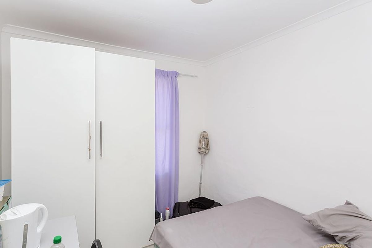 A functional bedroom featuring a built-in wardrobe and neutral finishes, offering a blank canvas for personalization.
