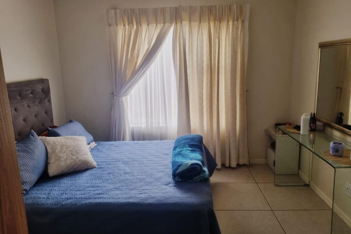 A bedroom featuring tiled flooring and a window with curtains.