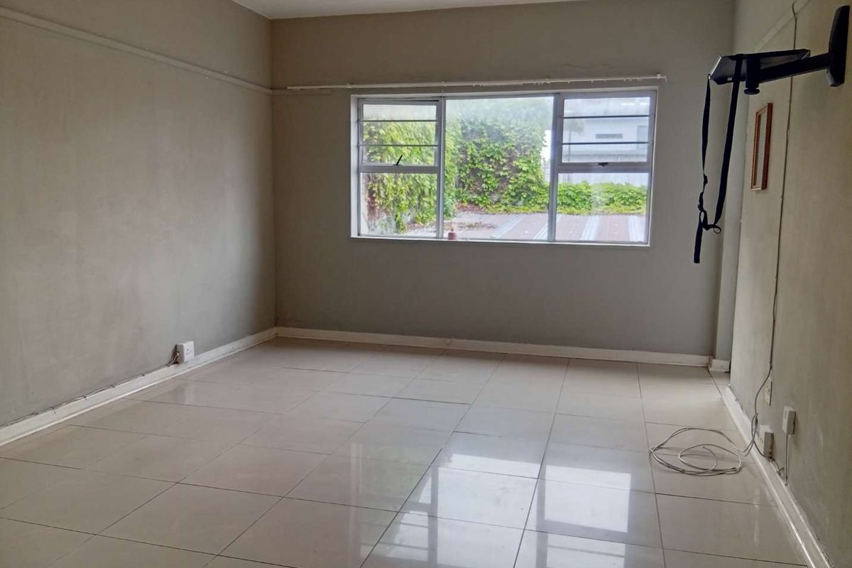 An empty living room featuring tiled flooring and large windows, providing a blank canvas for interior design and renovation.