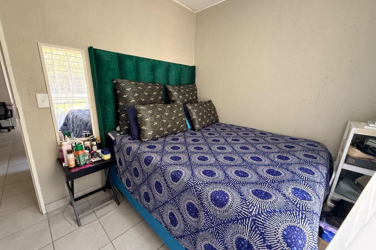 A compact bedroom featuring tiled flooring and a neutral wall finish, providing a functional space for rest.