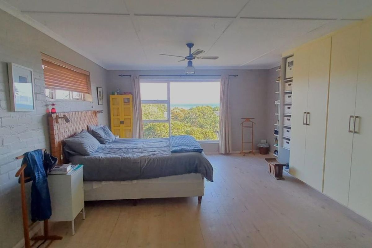 Spacious bedroom featuring large built-in wardrobes, a ceiling fan, and a large window offering scenic views.