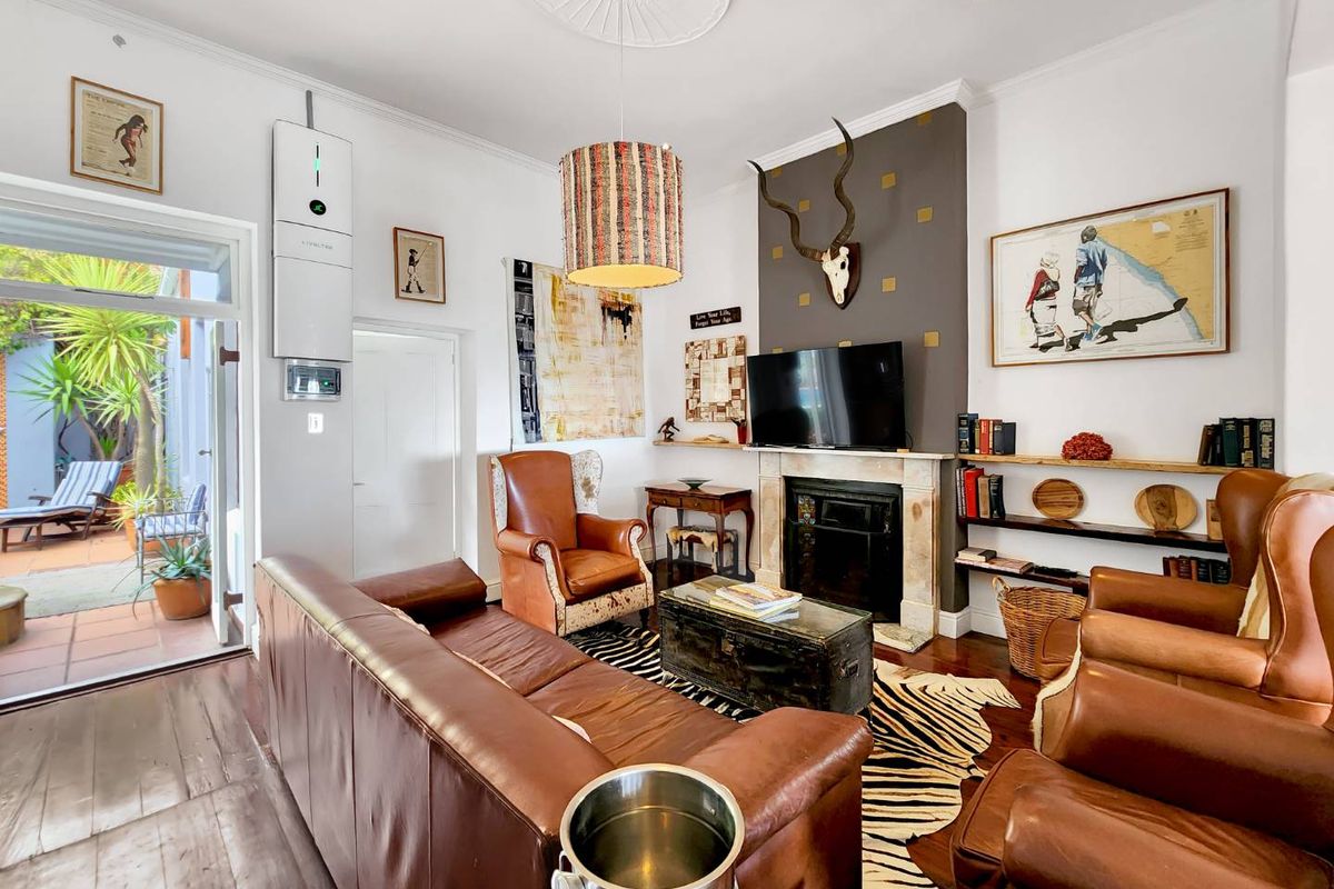 A well-maintained living room featuring a central fireplace with a mantelpiece, hardwood flooring, and direct access to an outdoor patio area.