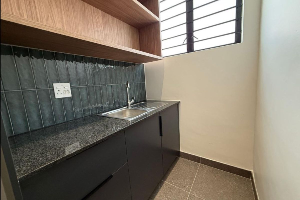 A modern, compact scullery featuring dark cabinetry, granite countertops, a stainless steel sink, and stylish tiled backsplash with open shelving.